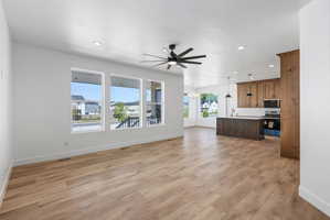 Open concept living space featuring wood-finish flooring, recessed lighting, and a dark-bladed ceiling fan