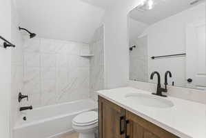 Bathroom featuring a white bathtub with a tiled surround, a wood-finish vanity with a white countertop, a single undermount sink, and matte black fixtures