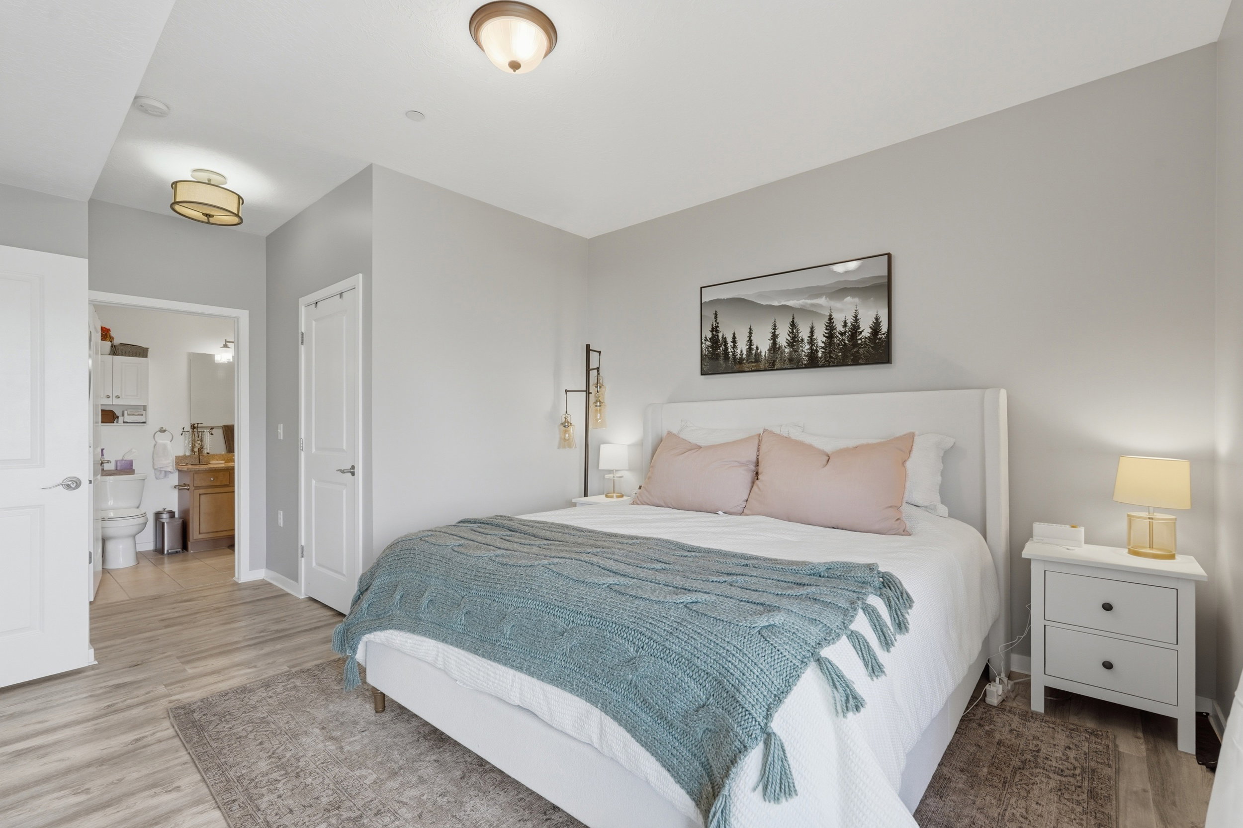 Bedroom featuring light wood-style floors, a closet, and ensuite bath