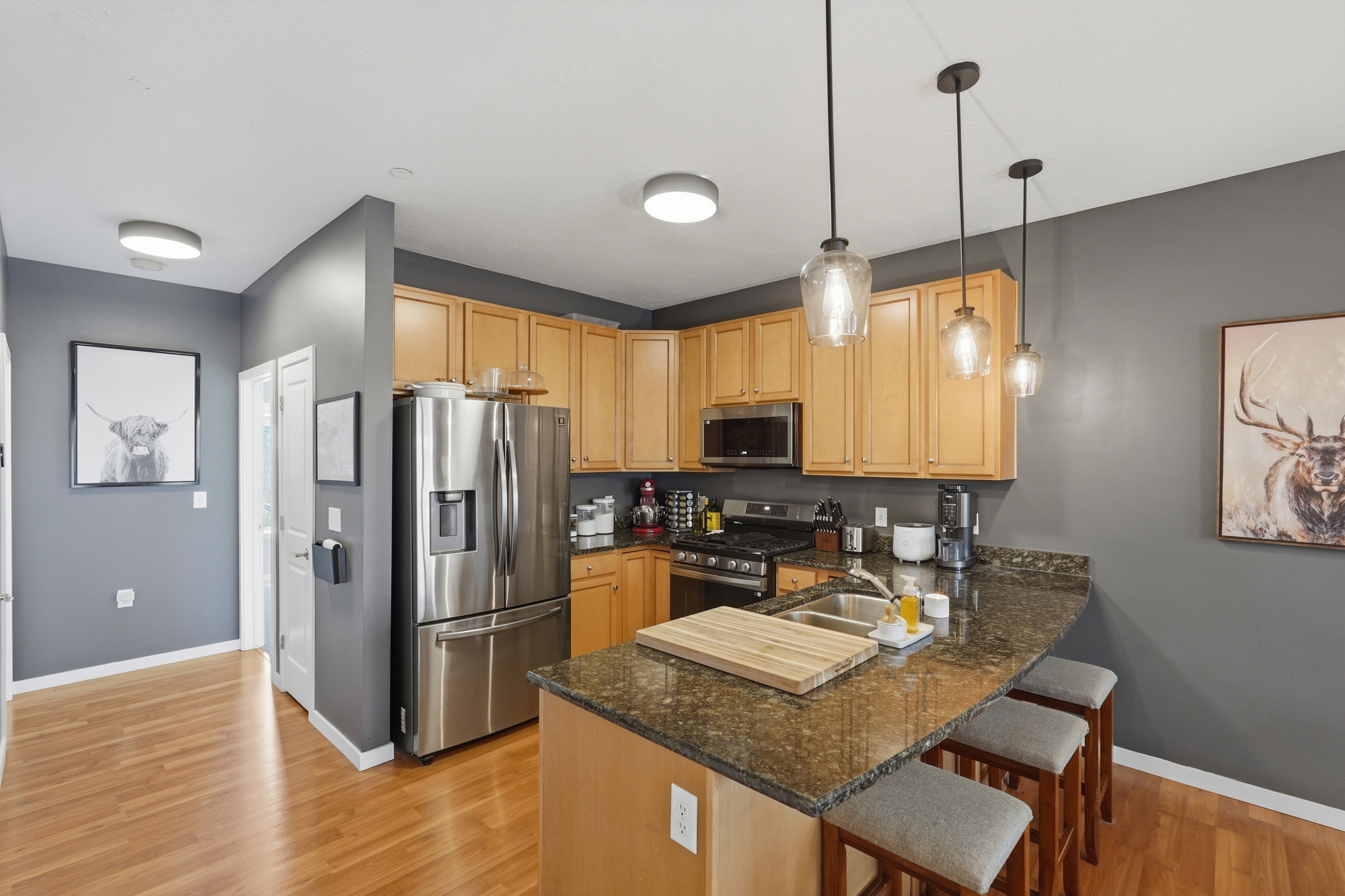 Kitchen with stainless steel appliances, a breakfast bar, pendant lighting, a peninsula, and dark stone countertops