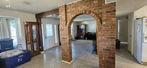Entrance foyer with a textured ceiling, arched walkways, and speckled floor