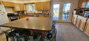 Kitchen with a breakfast bar area, stainless steel appliances, dark countertops, and a kitchen island
