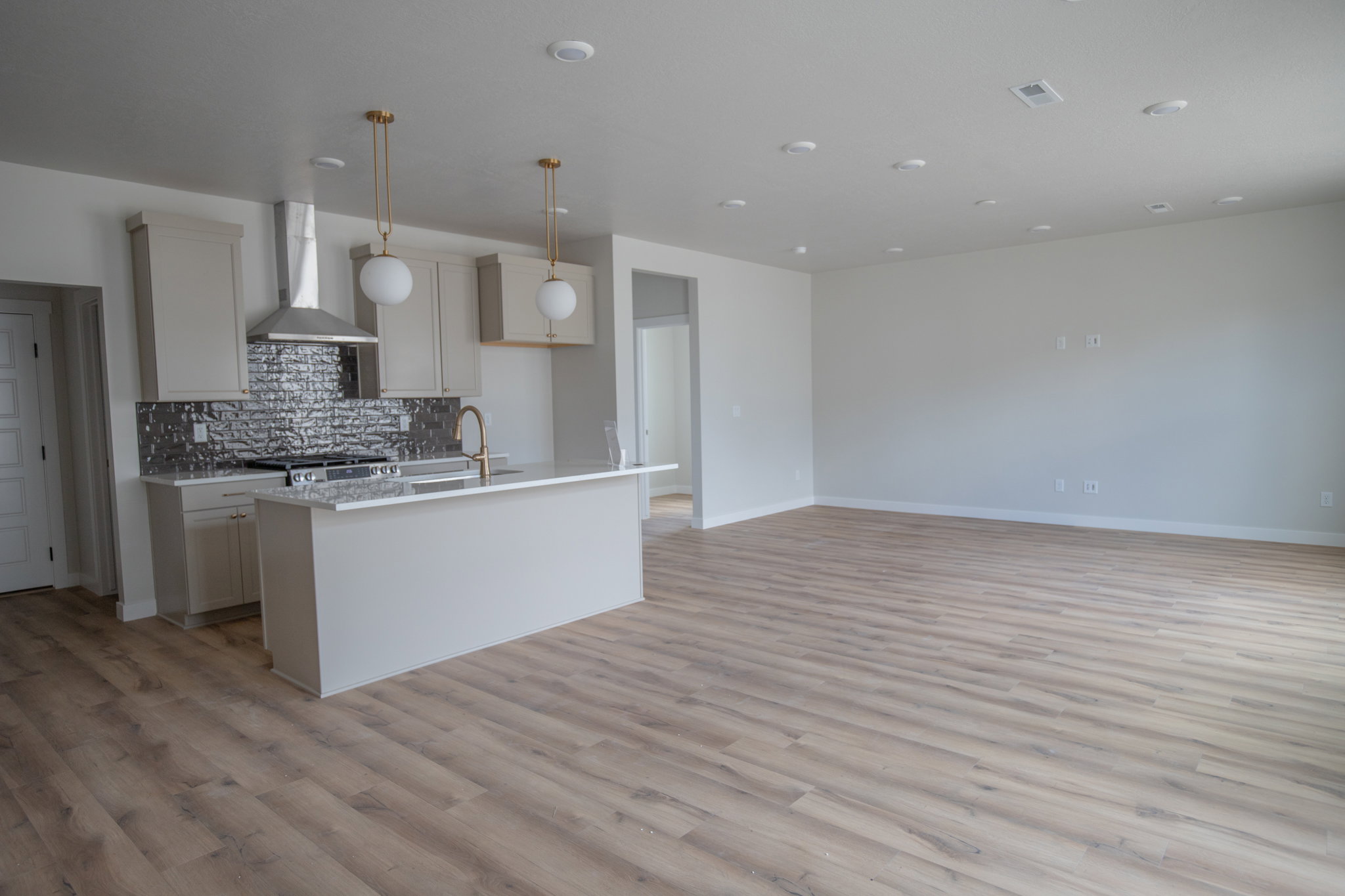 Open-concept living area featuring wood-finish flooring, recessed lighting, and a kitchen island with pendant lighting