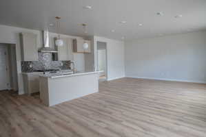 Open-concept living area featuring wood-finish flooring, recessed lighting, and a kitchen island with pendant lighting