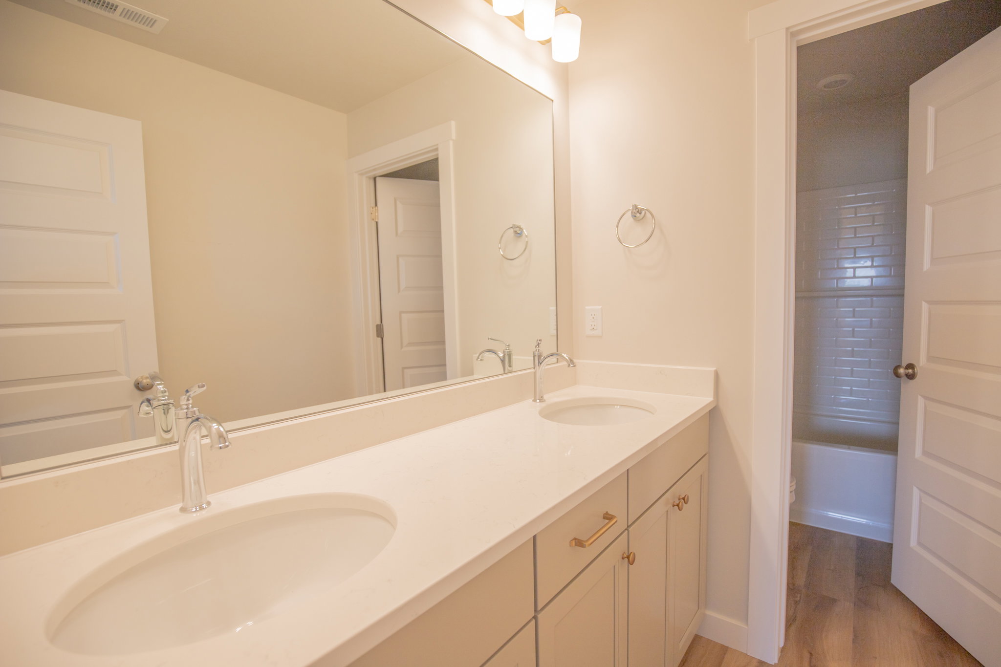 Double vanity featuring integrated sinks, chrome fixtures, light-toned countertops, and soft-close cabinetry with gold-tone hardware