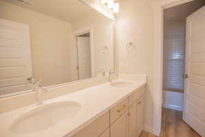 Double vanity featuring integrated sinks, chrome fixtures, light-toned countertops, and soft-close cabinetry with gold-tone hardware