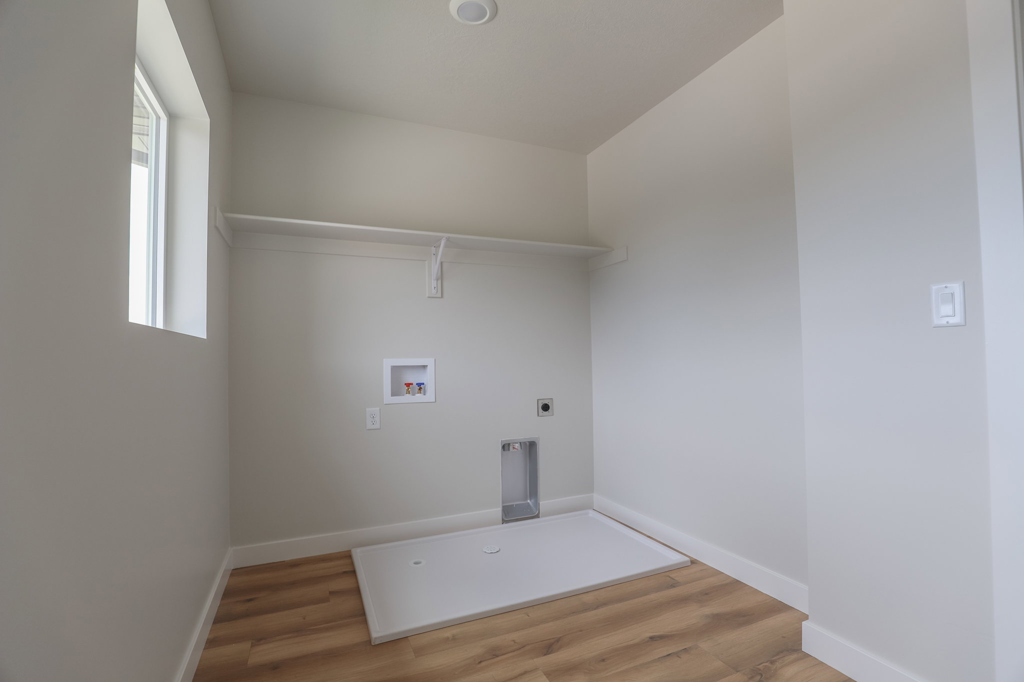 Dedicated laundry room featuring wood-finish flooring, white walls, and a recessed ceiling light