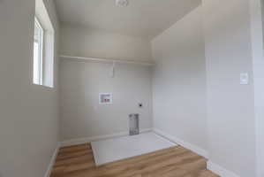 Dedicated laundry room featuring wood-finish flooring, white walls, and a recessed ceiling light
