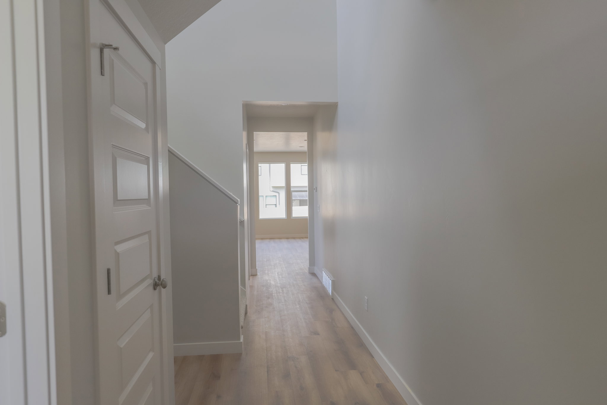 Hallway featuring light wood-finish flooring, white baseboards, and neutral wall paint