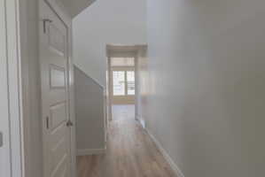 Hallway featuring light wood-finish flooring, white baseboards, and neutral wall paint
