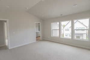Spacious interior featuring a vaulted ceiling, recessed lighting, and soft gray carpeting