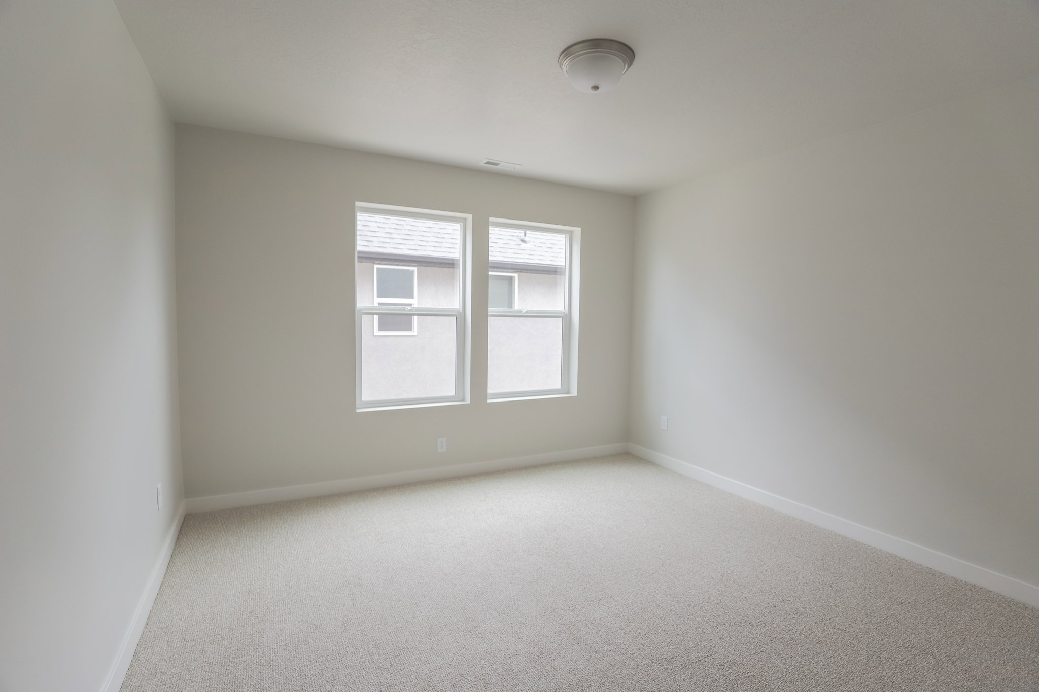 Light-filled interior space featuring neutral wall tones, two large windows, and plush carpet flooring