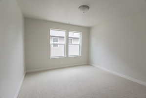 Light-filled interior space featuring neutral wall tones, two large windows, and plush carpet flooring
