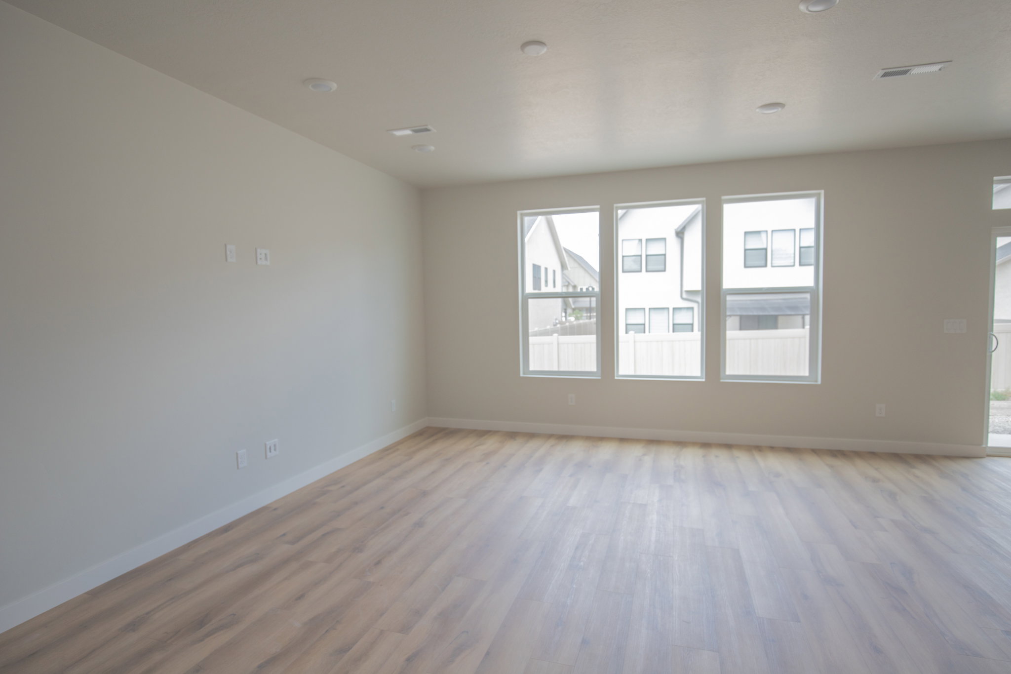 Spacious room featuring light wood-finish flooring, recessed lighting, and three large windows
