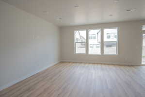 Spacious room featuring light wood-finish flooring, recessed lighting, and three large windows