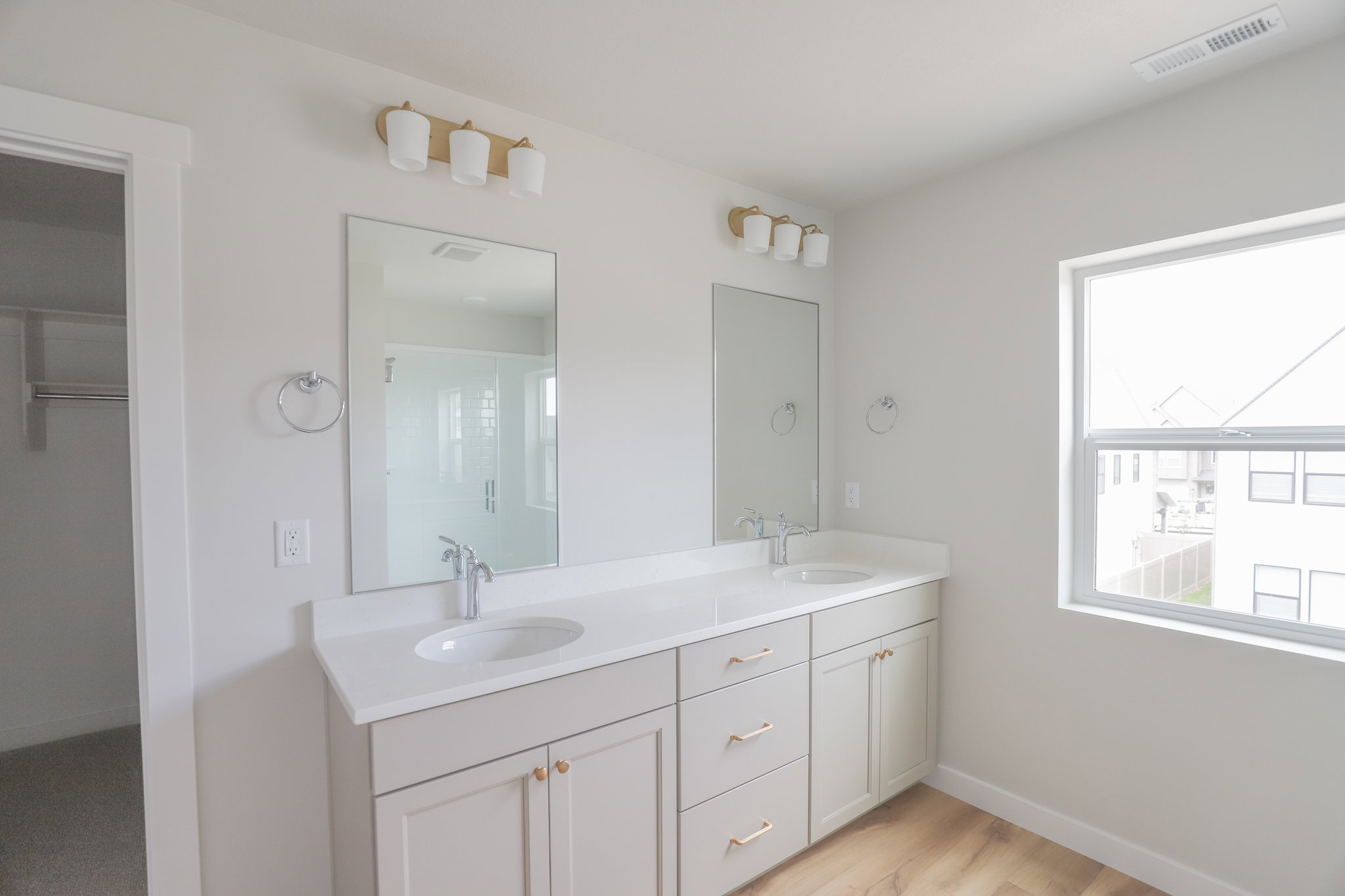 Dual vanity featuring white countertops, undermount sinks, and light-toned cabinetry with gold-toned hardware