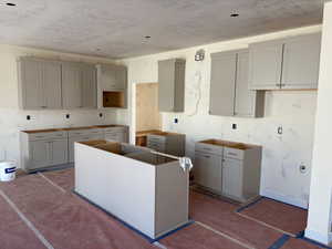 Kitchen featuring gray cabinetry, a textured ceiling, and a kitchen island