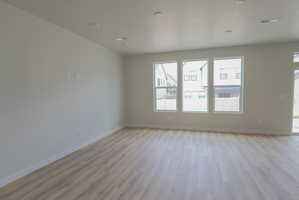 Spacious interior room featuring wood-finish flooring, recessed lighting, and multiple windows with white frames