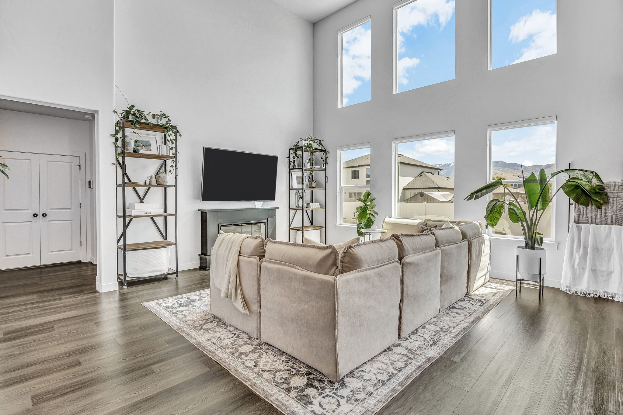 Living area with a high ceiling, dark wood-type flooring, and a glass covered fireplace