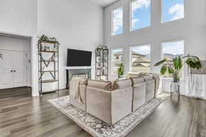 Living area with a high ceiling, dark wood-type flooring, and a glass covered fireplace