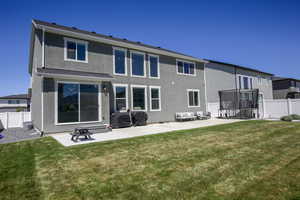 Rear view of house with a fenced backyard, a trampoline, stucco siding, and a patio