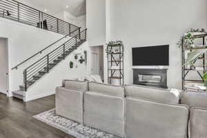 Living room featuring dark wood-style floors, a high ceiling, and a glass covered fireplace