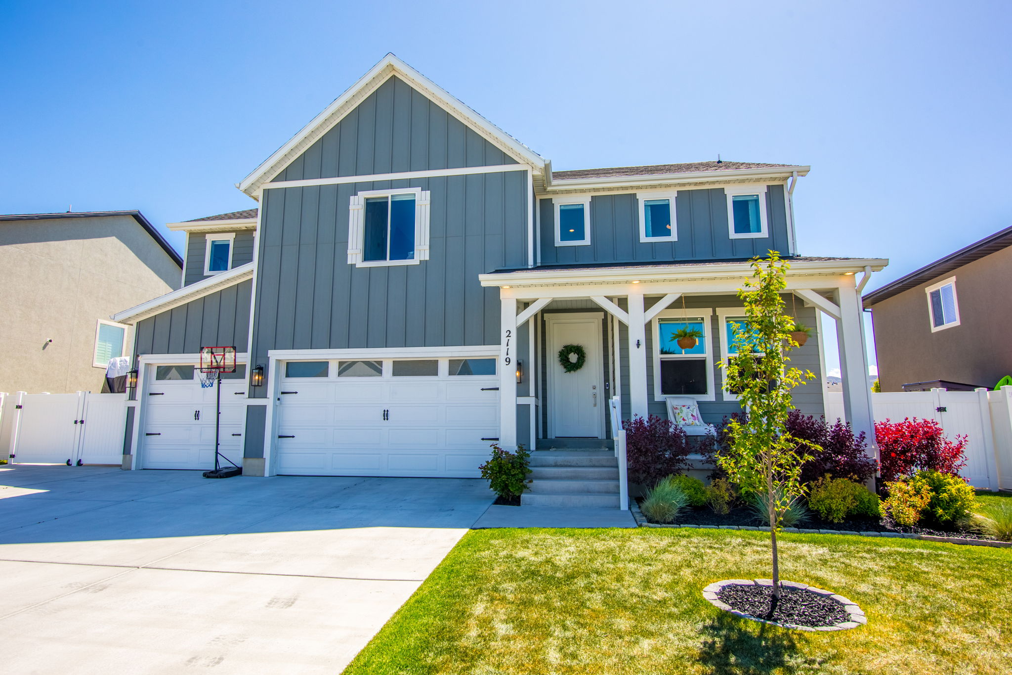 View of front facade with a gate, board and batten siding, a porch, concrete driveway, and a garage