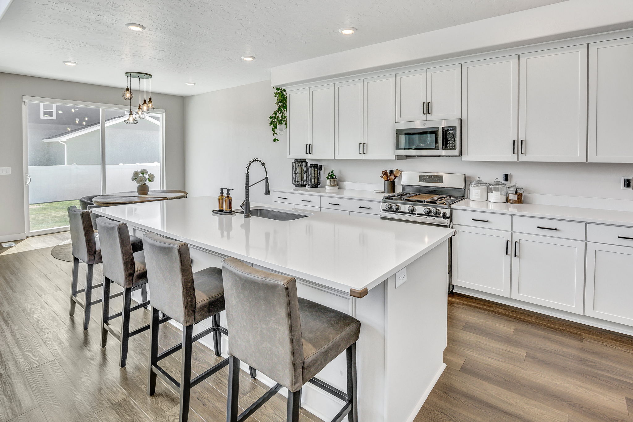 Kitchen featuring a kitchen island with sink, white cabinets, a kitchen bar, stainless steel appliances, and a textured ceiling