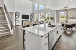 Kitchen featuring a kitchen breakfast bar, white cabinetry, an island with sink, open floor plan, and a fireplace