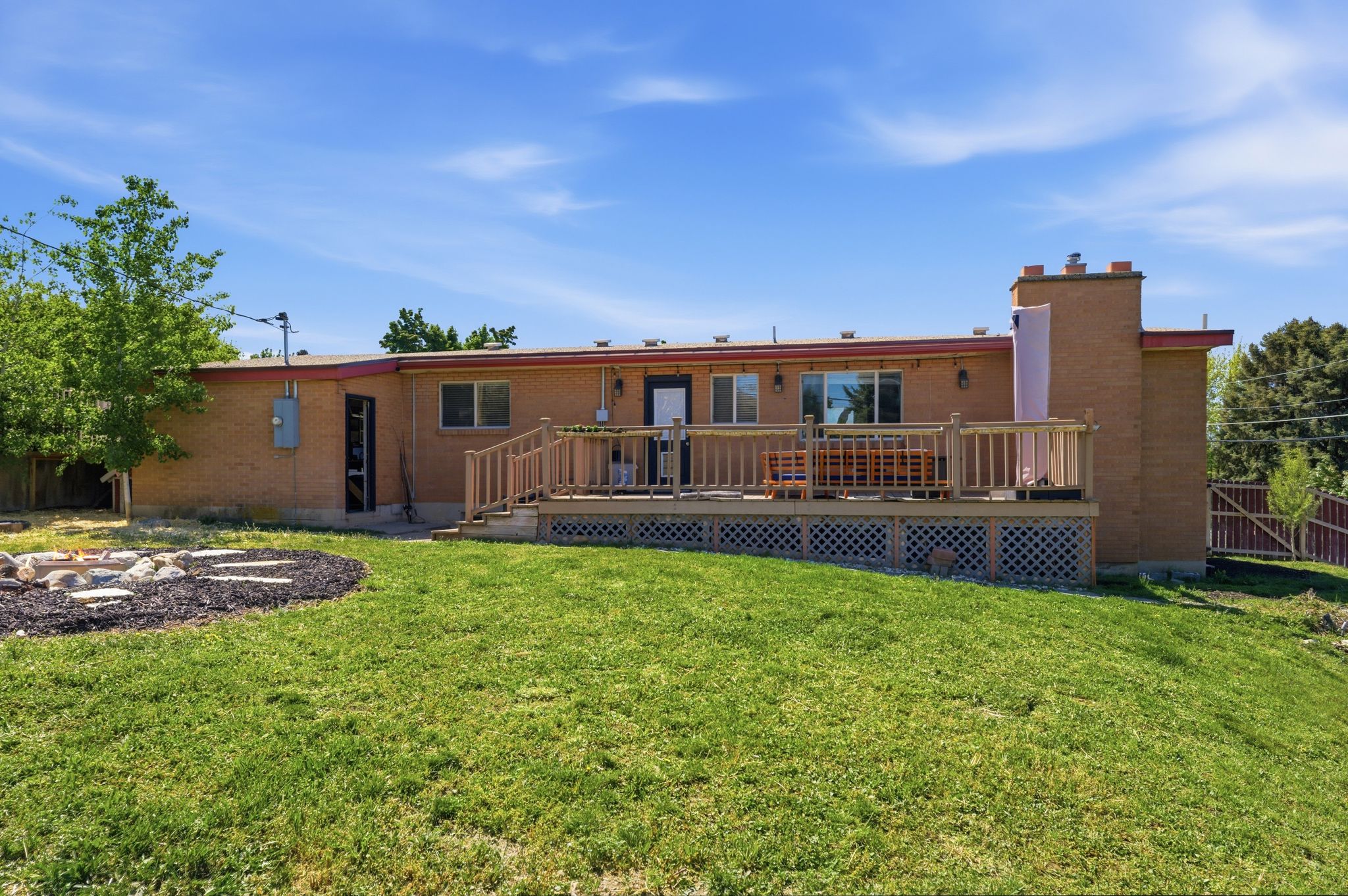 Back of property featuring a deck, brick siding, and a chimney