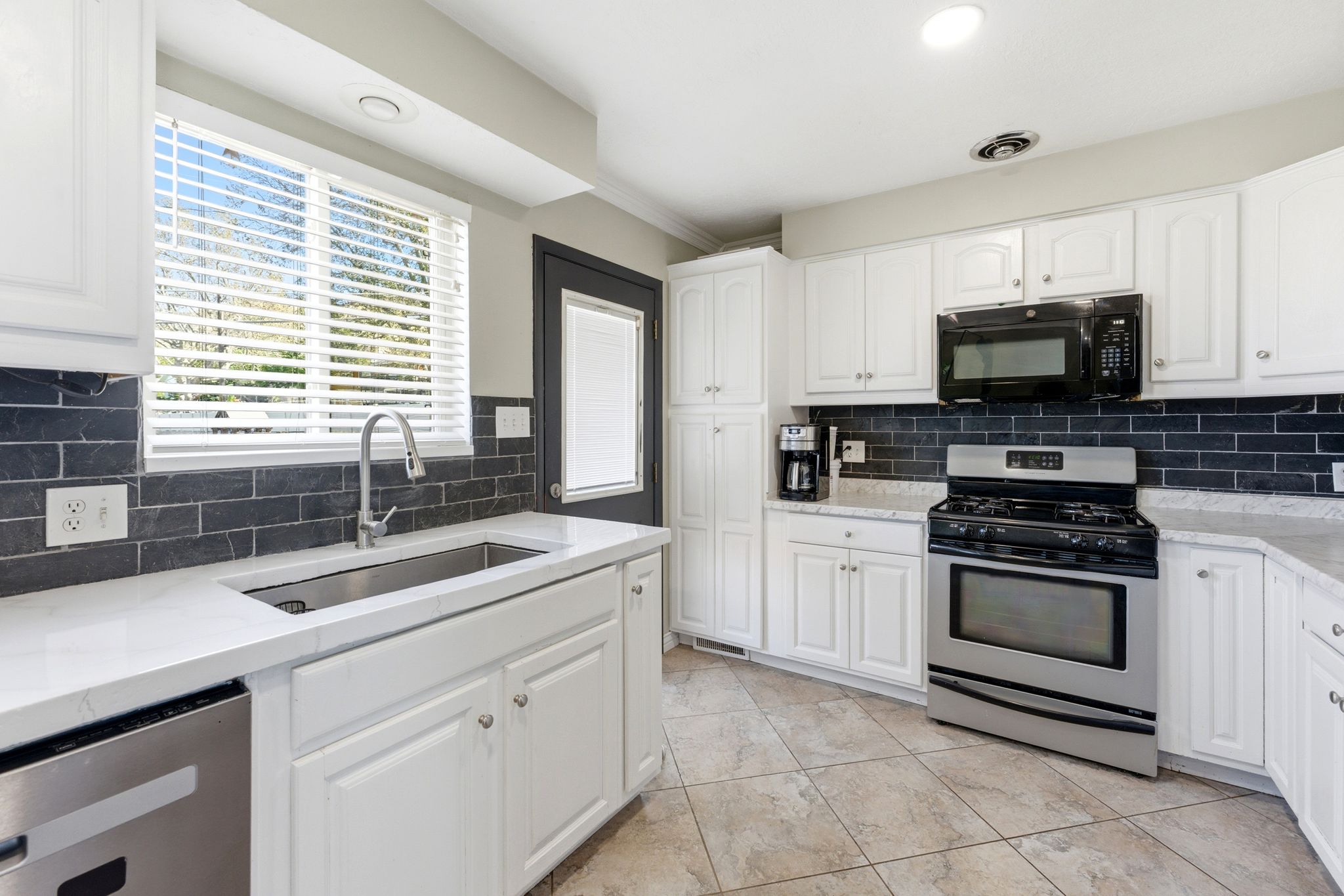 Kitchen featuring stainless steel appliances, light stone counters, white cabinetry, crown molding, and recessed lighting