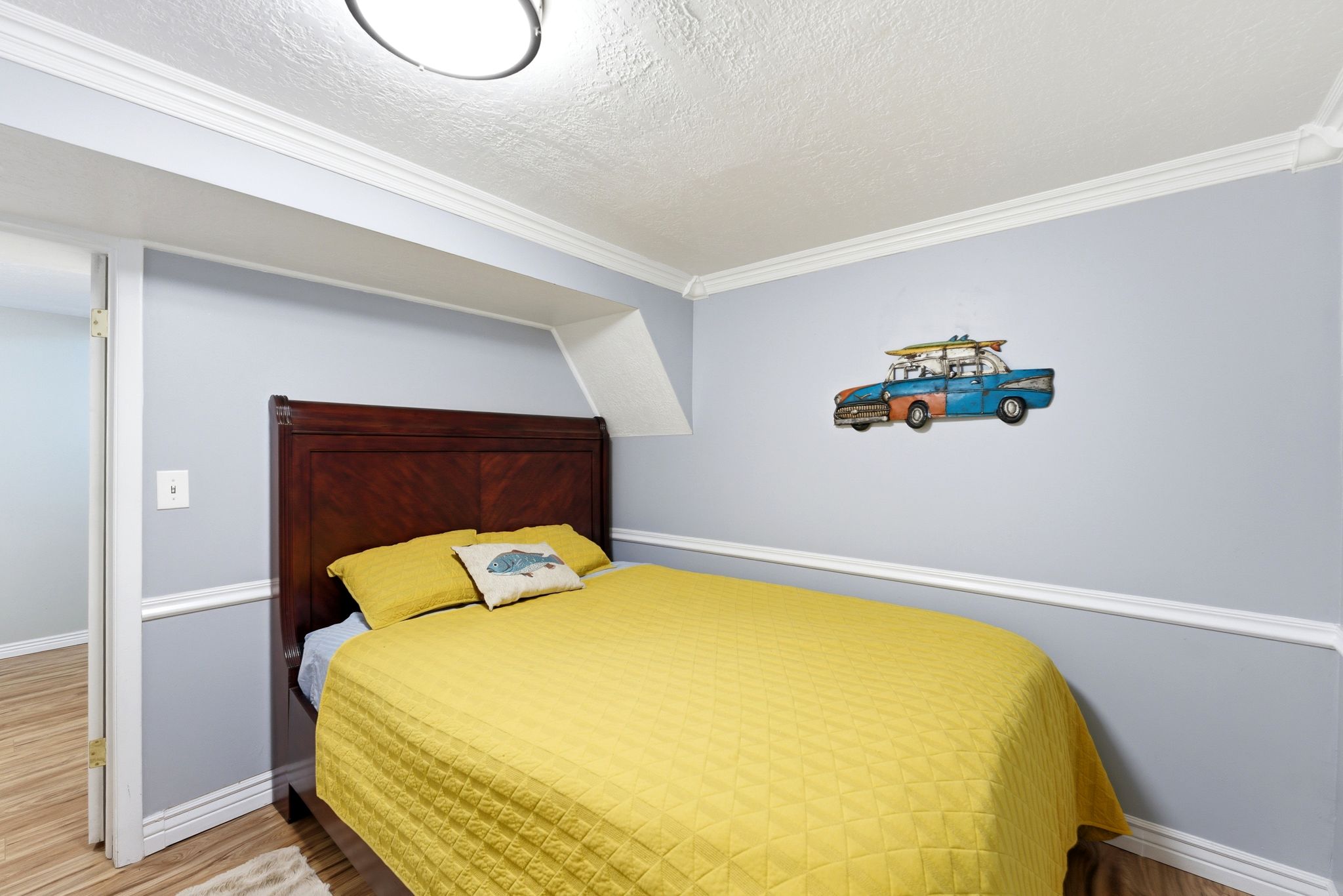 Bedroom with wood finished floors, a textured ceiling, and crown molding