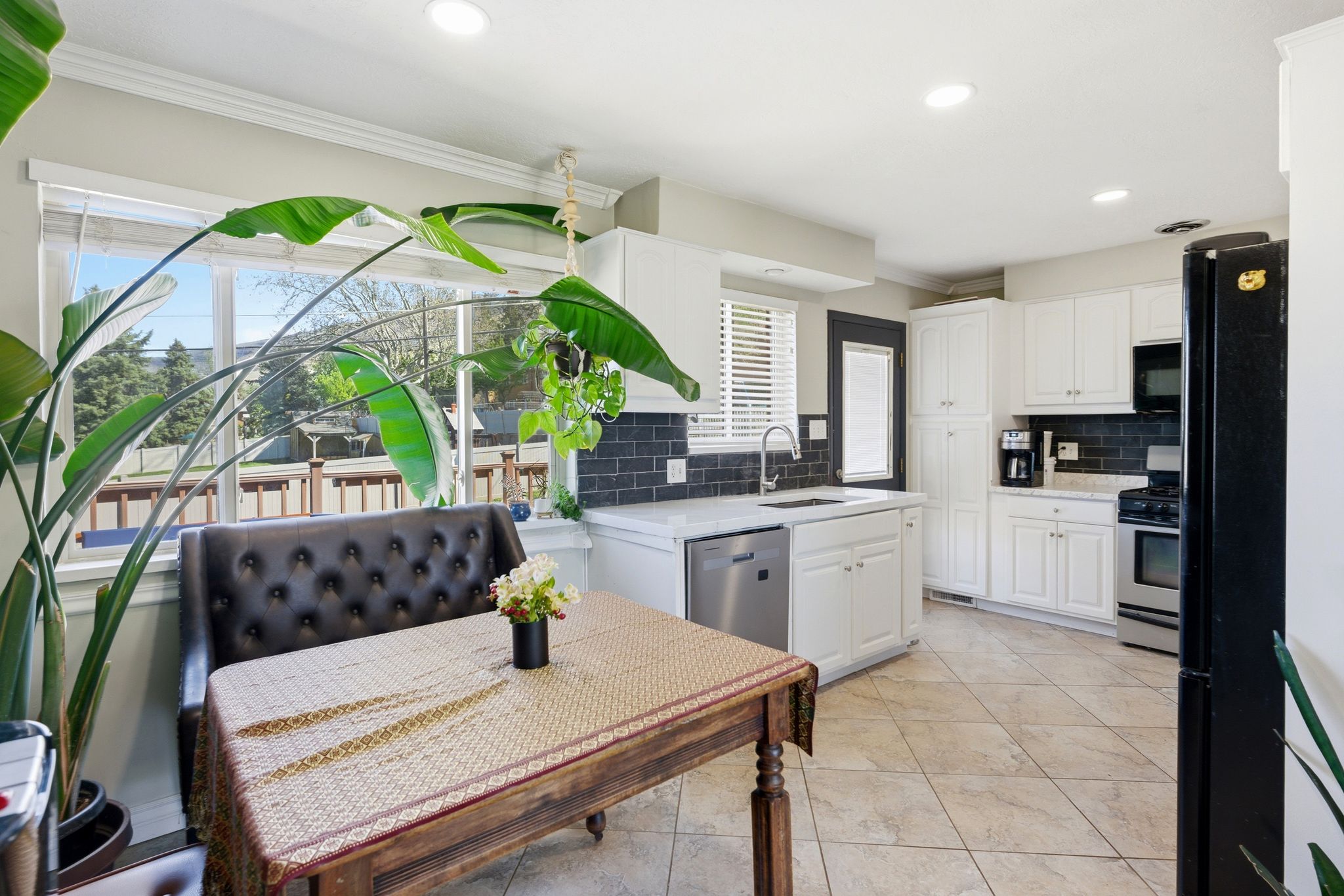 Kitchen with white cabinetry, black appliances, ornamental molding, light stone counters, and recessed lighting