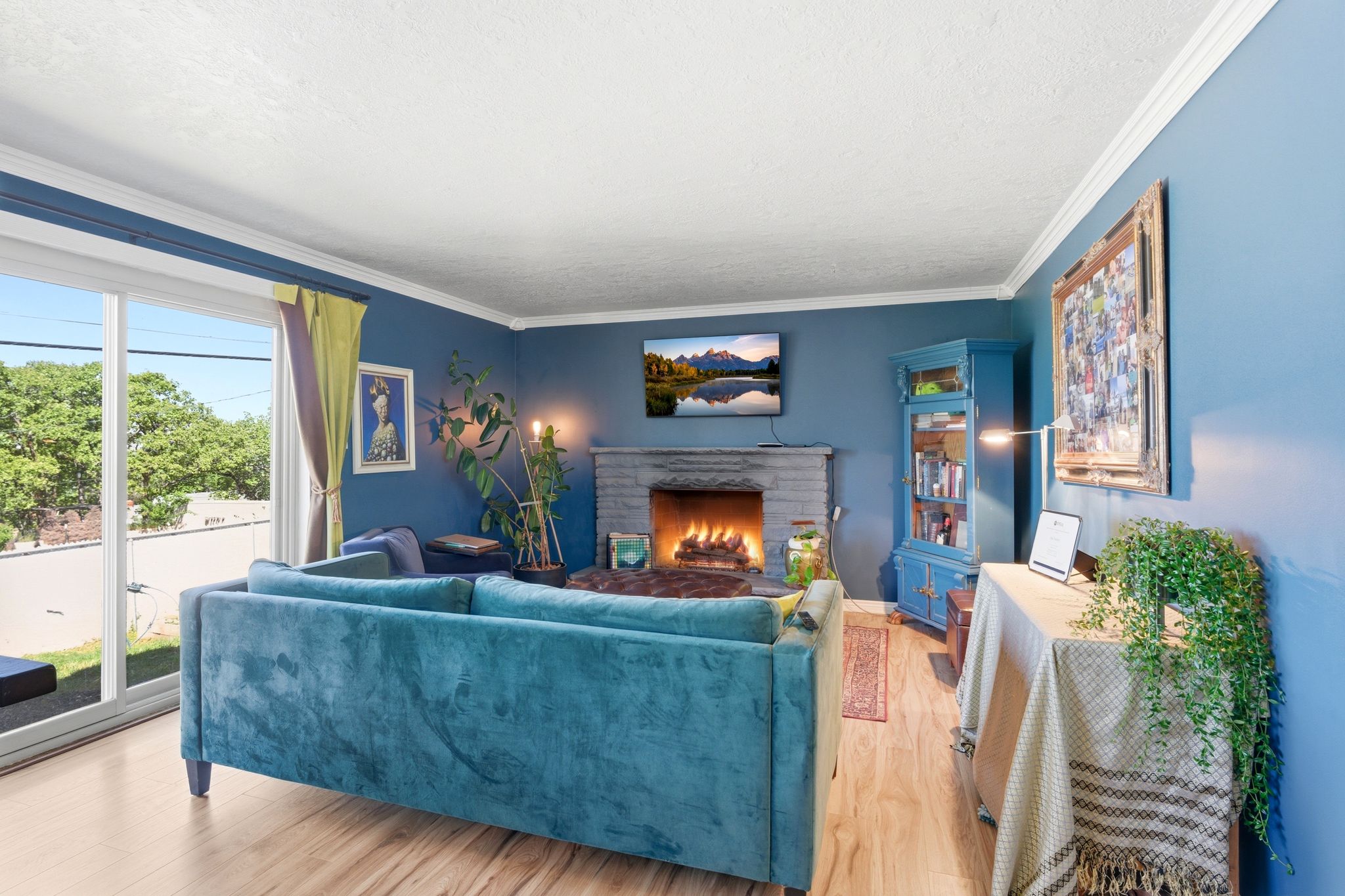 Living area with light wood-style flooring, a lit fireplace, a textured ceiling, and ornamental molding