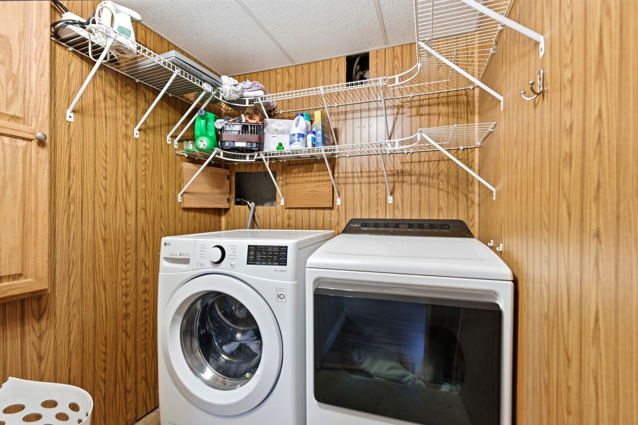 Laundry area featuring wood walls, washing machine and clothes dryer, and a paneled ceiling