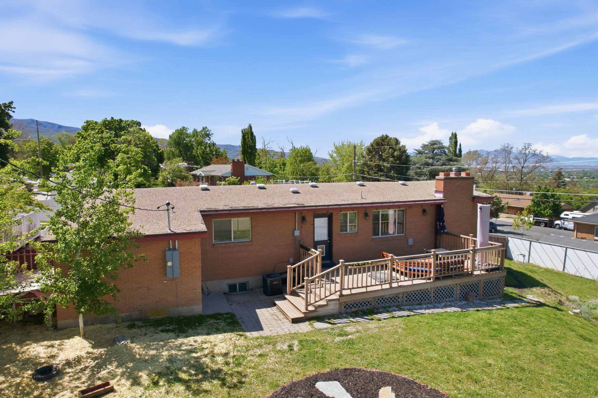 Rear view of house featuring a deck with mountain view, a chimney, a patio area, and brick siding