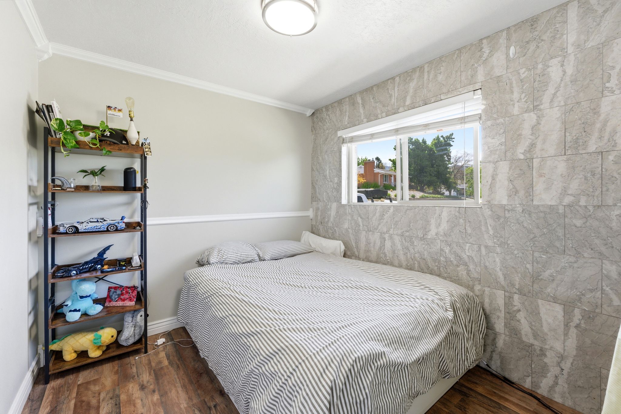 Bedroom with dark wood-style floors, ornamental molding, and tile walls