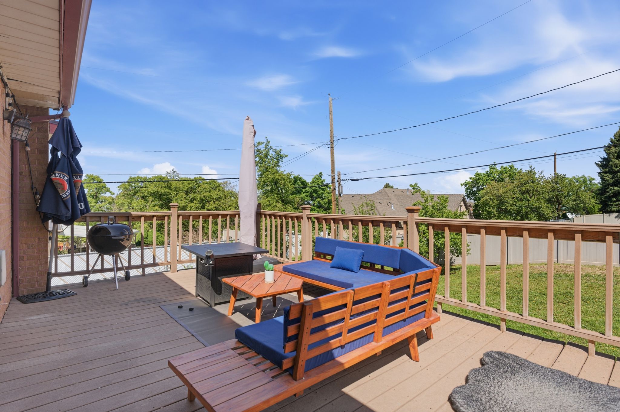 Wooden terrace with an outdoor lounge area, area for grilling, and a lawn