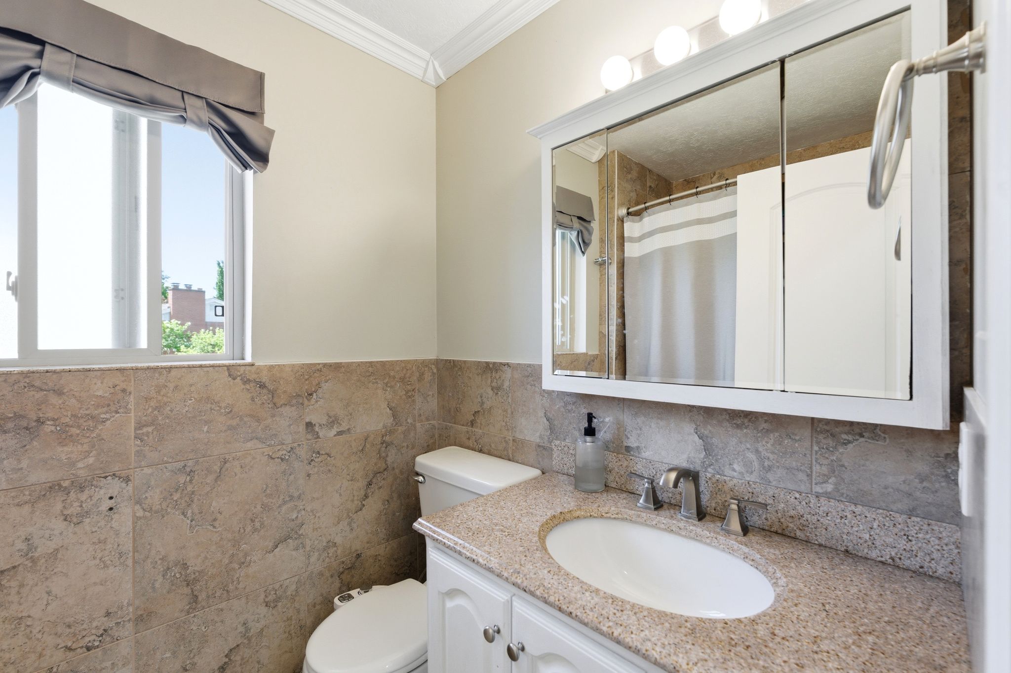 Bathroom with vanity, ornamental molding, a shower with curtain, a wainscoted wall, and tile walls