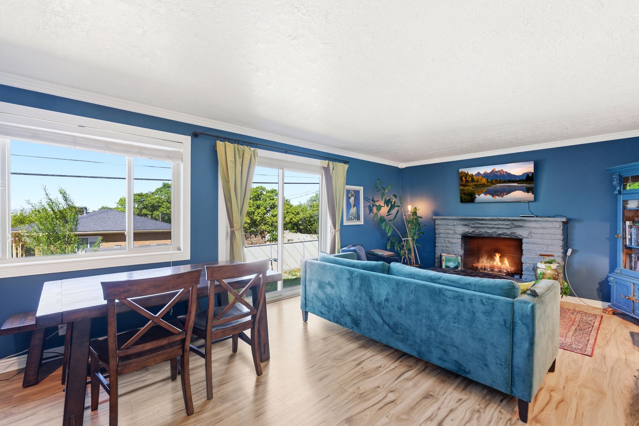 Living room featuring light wood-style flooring, a stone fireplace, a textured ceiling, and crown molding