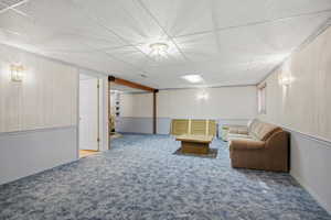Sitting room with a wainscoted wall, a paneled ceiling, and wood walls