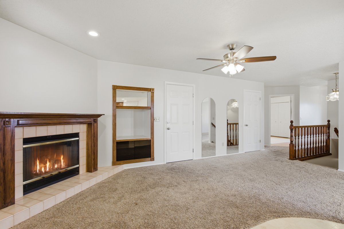 Unfurnished living room featuring carpet, a ceiling fan, a fireplace, and arched walkways