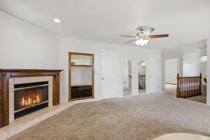 Unfurnished living room featuring carpet, a ceiling fan, a fireplace, and arched walkways