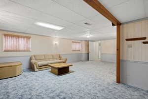 Living area with carpet floors, a drop ceiling, and healthy amount of natural light