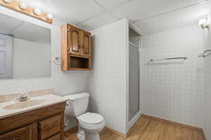 Full bath with vanity, a stall shower, light wood-type flooring, and wallpapered walls