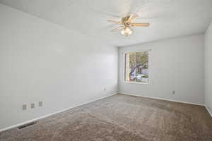 Empty room featuring carpet flooring, a ceiling fan, and a textured ceiling