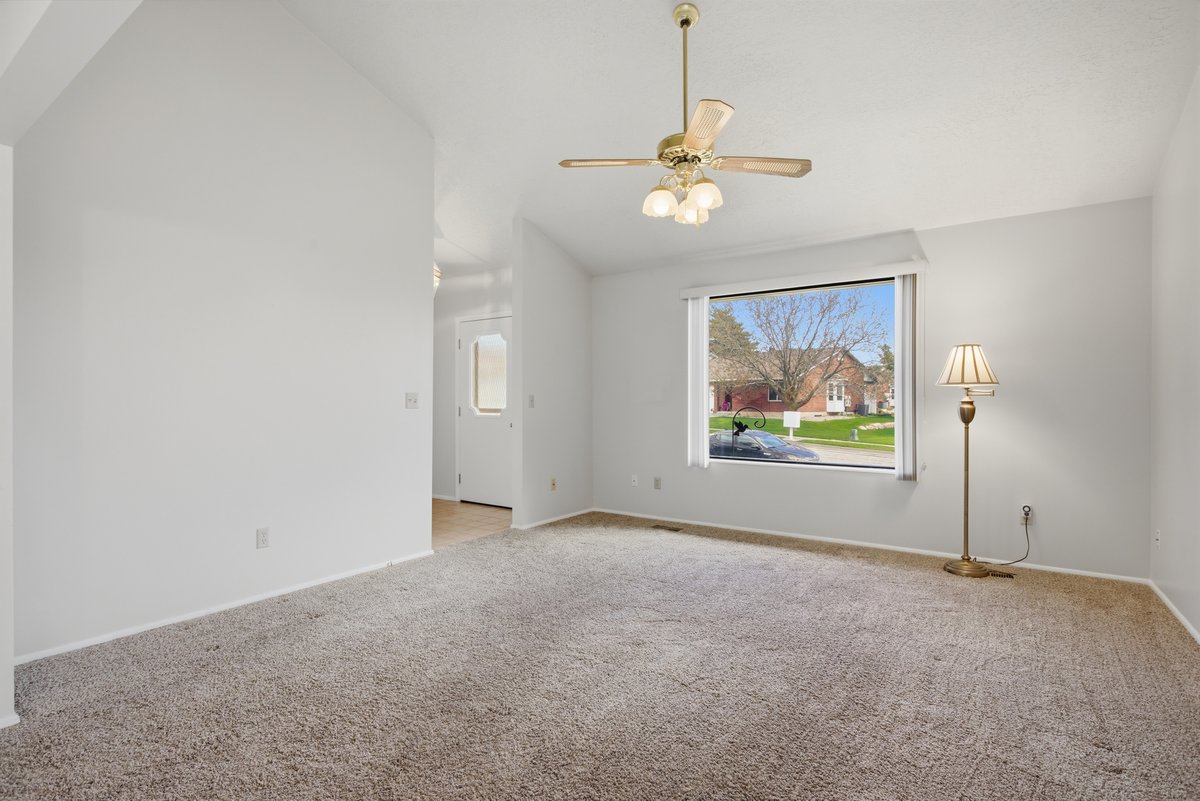Empty room featuring carpet flooring, lofted ceiling, and ceiling fan