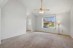 Empty room featuring carpet flooring, lofted ceiling, and ceiling fan