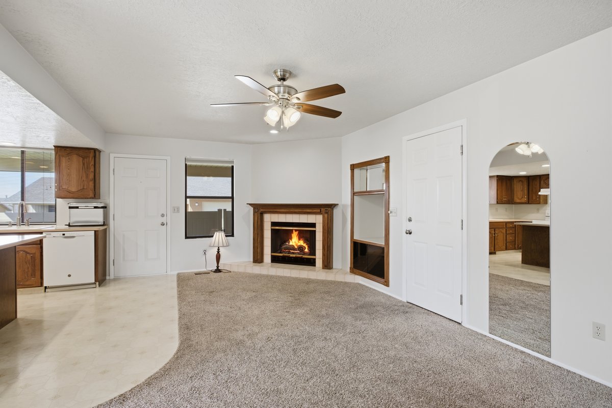 Unfurnished living room featuring ceiling fan, a fireplace, light carpet, arched walkways, and a textured ceiling