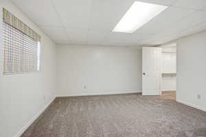 Unfurnished bedroom with a spacious closet, a paneled ceiling, and carpet